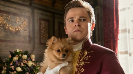 Sam Clemmett as young Brimsley in Queen Charlotte: A Bridgerton Story holding a small Pomeranian dog