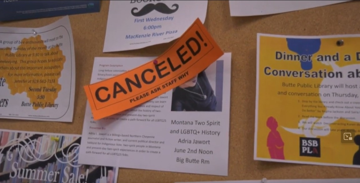 An orange sign that says "Canceled! Please Ask Staff Why" is pinned over a flier for Adria Jawort's scheduled speaking event on a bulletin board at the Butte-Silver Bow Public Library.