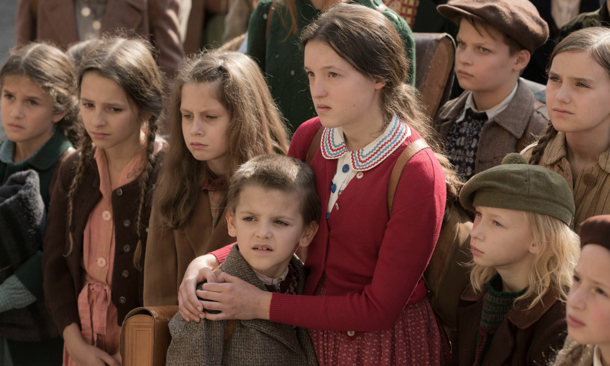 Bella Ramsey (center) embraces a little boy while standing with a group of children in the 2020 film 'Resistance'