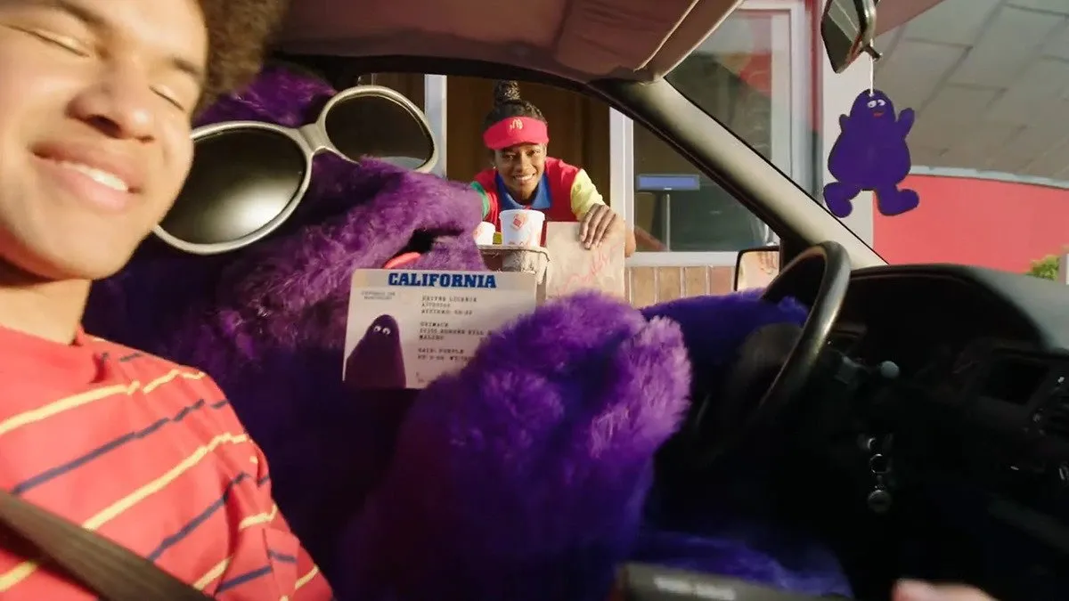 Grimace chilling and holding up his driver's license with someone in a car