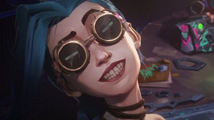 Image of Jinx from Netflix's animated series, 'Arcane.' Jinx is a white teenage girl with long blue hair. We see her from the shoulders up as she looks at us while wearing steampunk goggles and grinning maniacally.