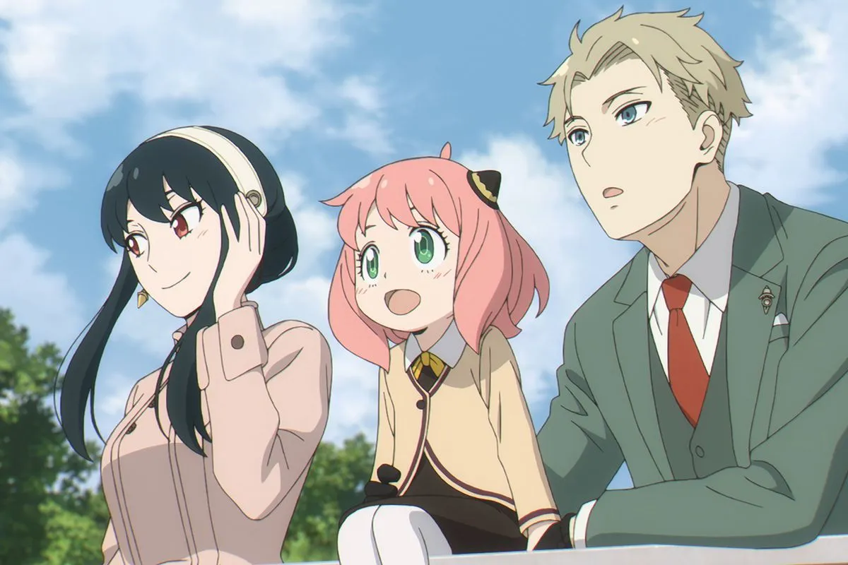 The cast of the anime series 'Spy x Family.' (l-r): Yor Briar (woman with long dark hair), Anya (young girl with a pink bob and bangs wearing a school uniform), and Loid (man with short blond hair wearing a 3-piece suit) are standing at a railing (Anya is sitting on the railing) looking out at something.