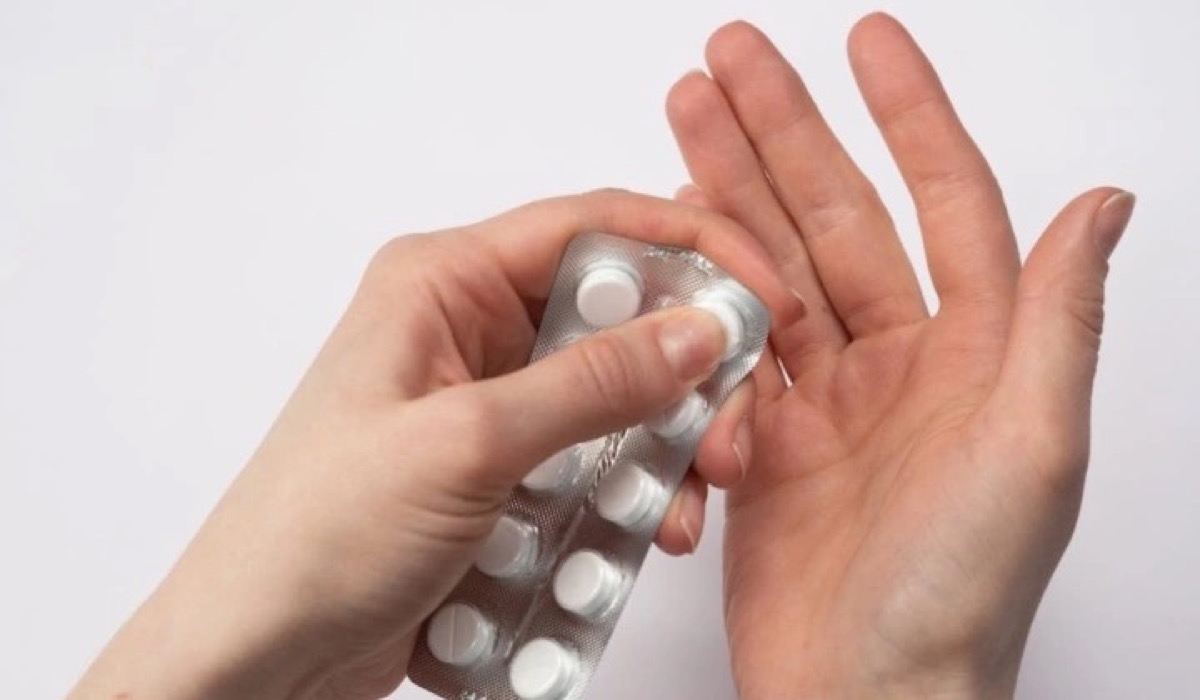 Someone extracting a pill from its packet