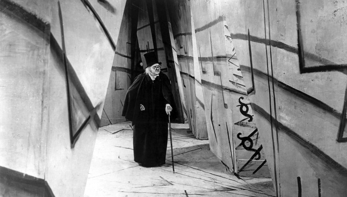 Dr. Caligari walks through a spooky hallways with weird linear designs on the walls in "The Cabinet of Dr. Caligari"