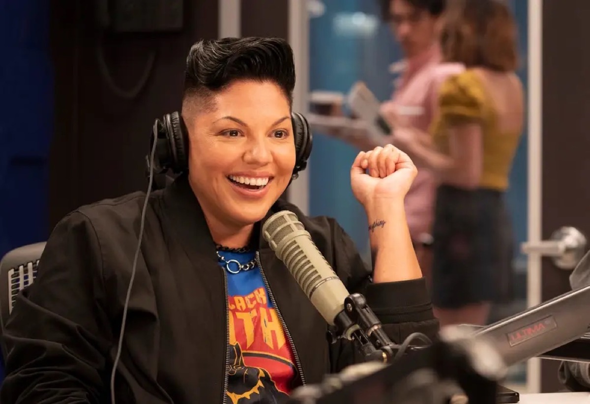 Che Diaz sitting at a microphone and smiling in Max's And Just Like That.