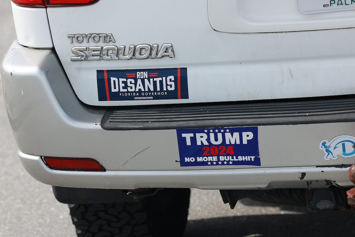 A Florida Gov. Ron DeSantis sticker and one reading, 'Trump 2024 No More Bullshit', are displayed on a white car.