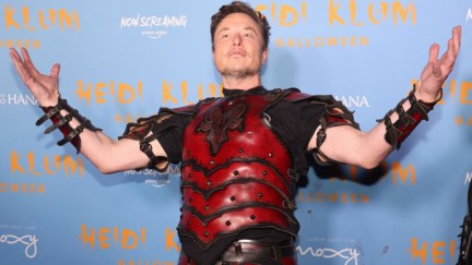 Elon Musk attends Heidi Klum's 2022 Hallowe'en Party at Sake No Hana at Moxy LES on October 31, 2022 in New York City. He's wearing costume armor and smugly holding his arms up.