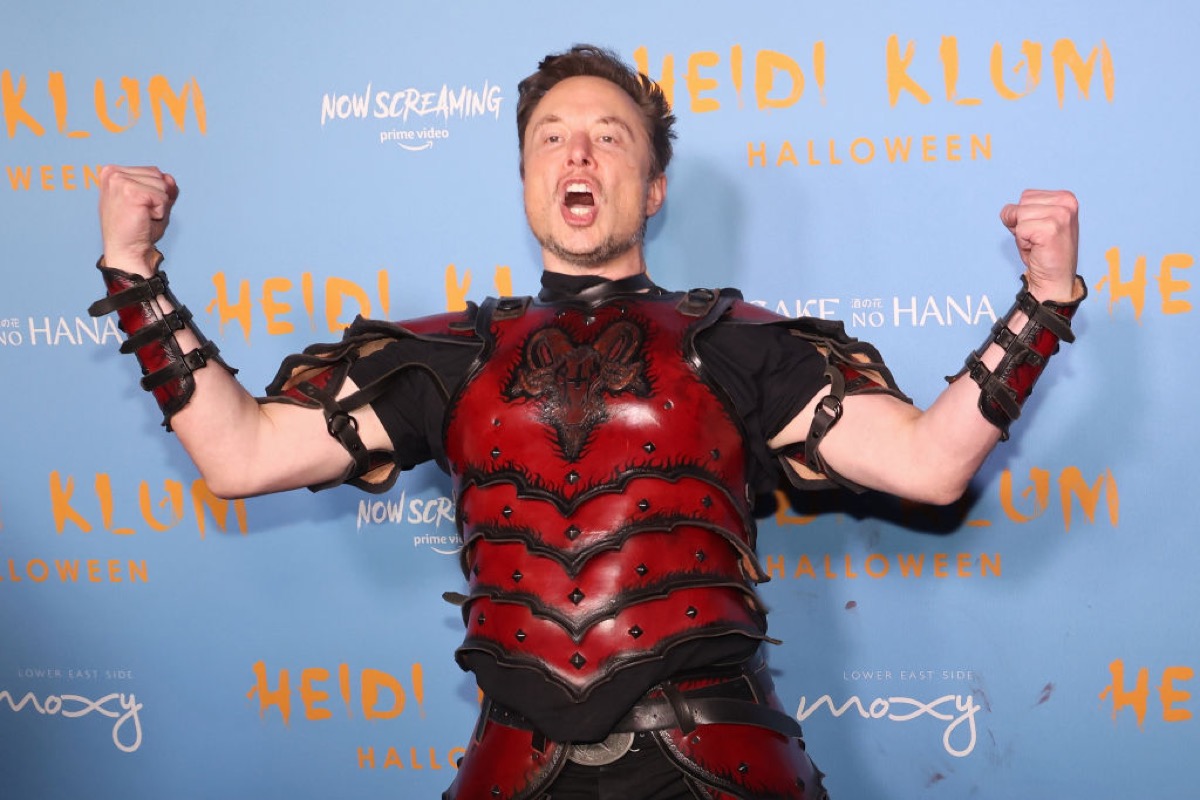 Elon Musk flexing like a doofus in weird armor at a Halloween party.