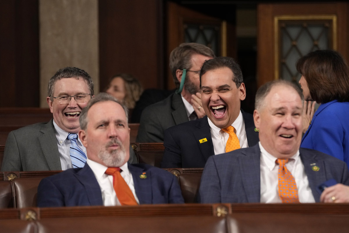 George Santos and some other Republicans sit and laugh.