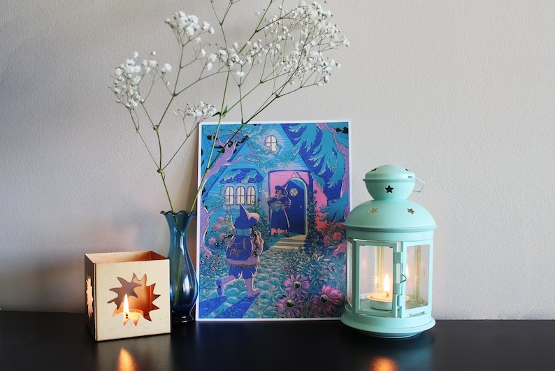 Homecoming by Rose Bousamra, a print of one witch returning home to her wife's house in the dark. The print is set on a shelf with a vase of flowers, a candle and a blue lantern.