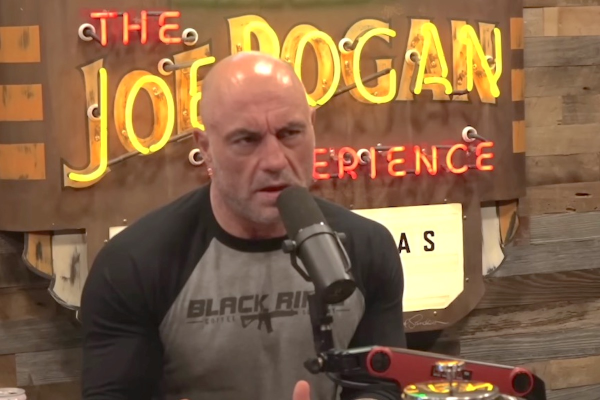 Joe Rogan records an episode of his podcast, speaking into a microphone and scowling.