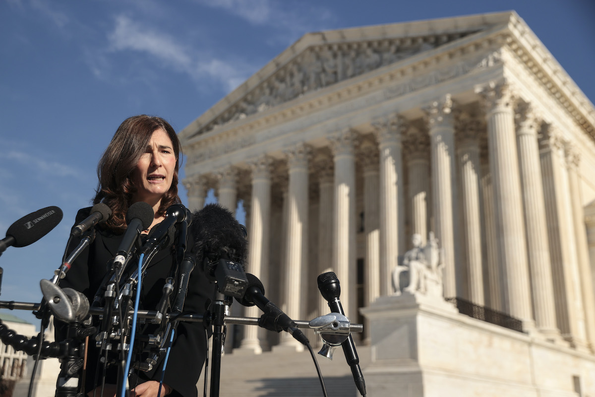 Julie Rikelman speaks at a press conference with the Supreme Court building in the background.