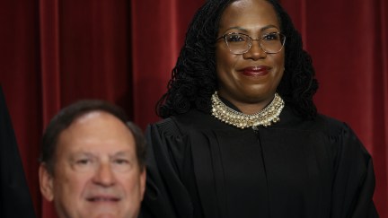 Ketanji Brown Jackson pictured behind Samuel Alito, posing for their official Supreme Court portrait.