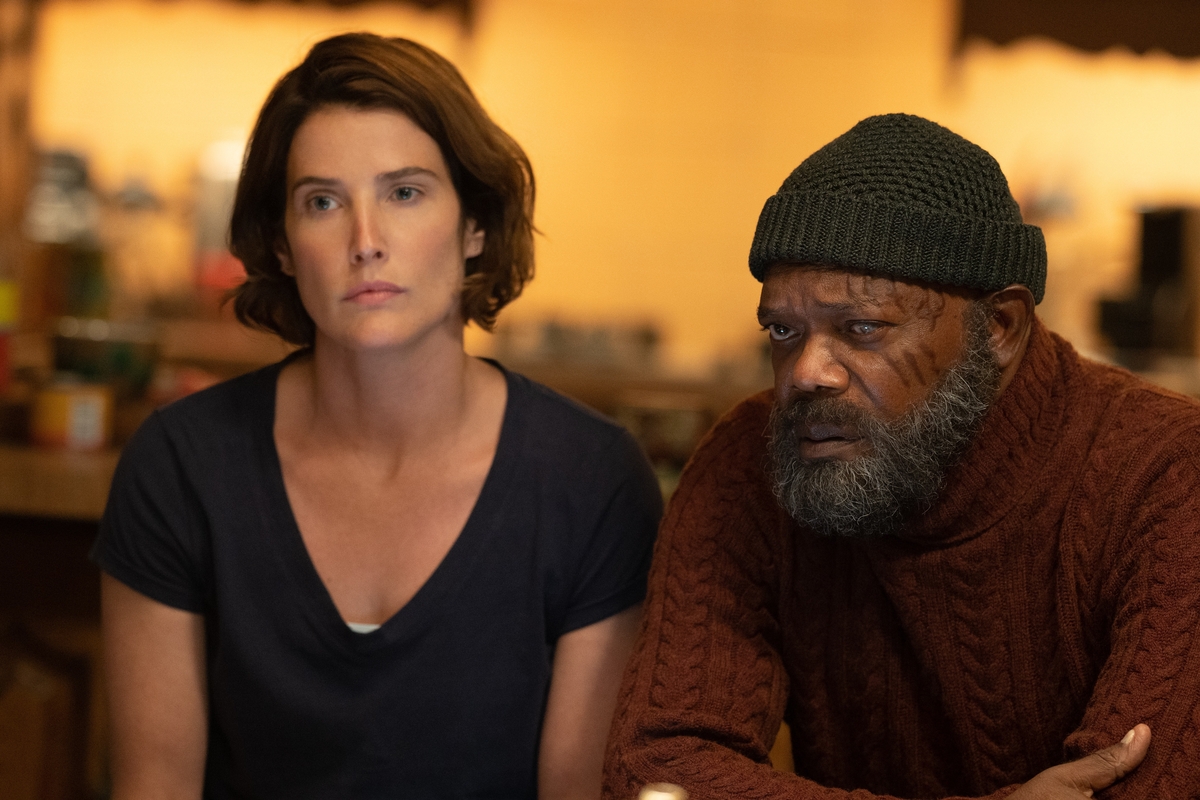Maria Hill and Nick Fury look at something off camera, sitting in a dimly lit room.