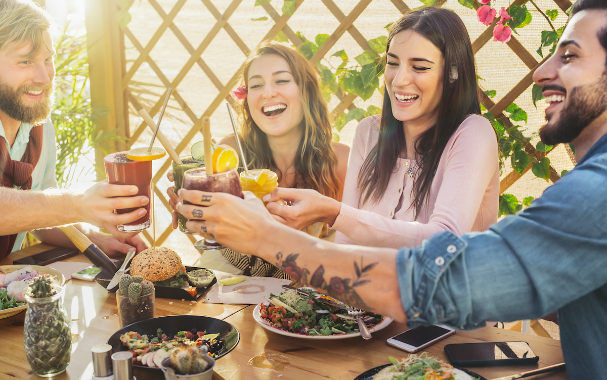 A group of white early-30s friends cheers over brunch.