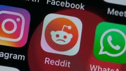 In this photo illustration, the logo of Reddit is seen on a smartphone screen, but the little alien figure's usual smile is a frown.