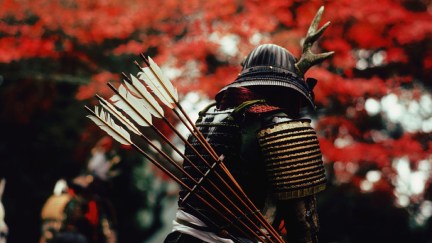 A person in samurai armor facing away from the camera, with a quiver full of arrows on his back.