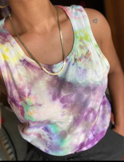 A rainbow tie-dyed tank top being modelled by a Black woman.