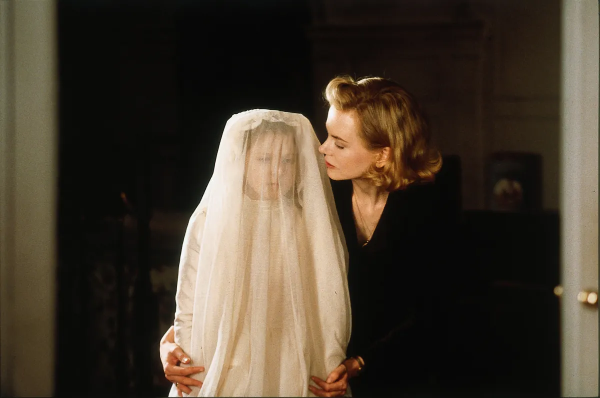 Nicole Kidman as Grace in "The Others" standing over a small child with a long white veil over it's face.