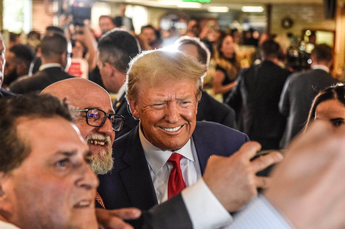 Donald Trump stands in a crowd of supporters, smiling for selfies.