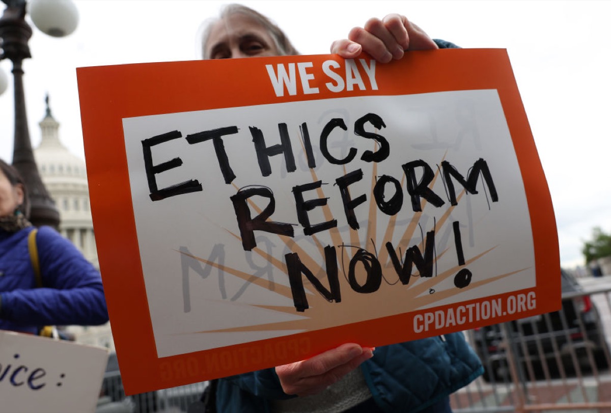 A protestor in front of the U.S. Supreme Court holding a sign that says "Ethics reform now!"