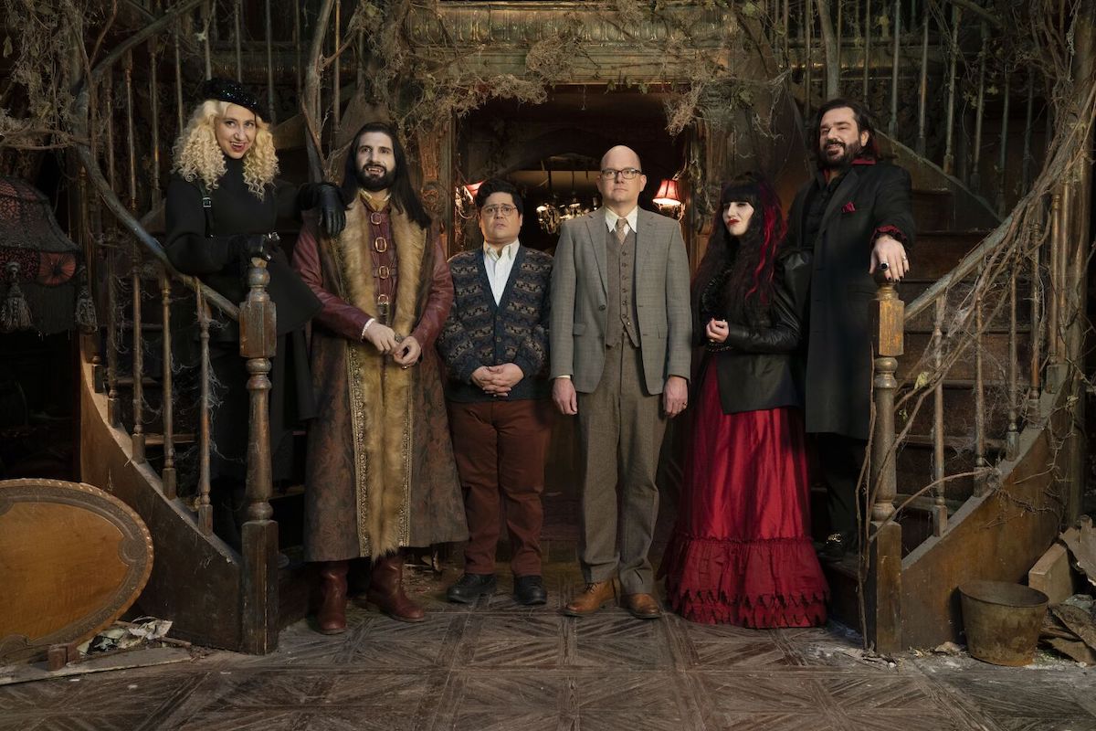The cast of What We Do in the Shadows stands in the foyer of their mansion.