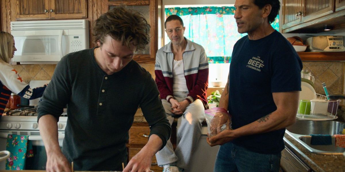 A group of people cook, eat, and talk in a family kitchen.
