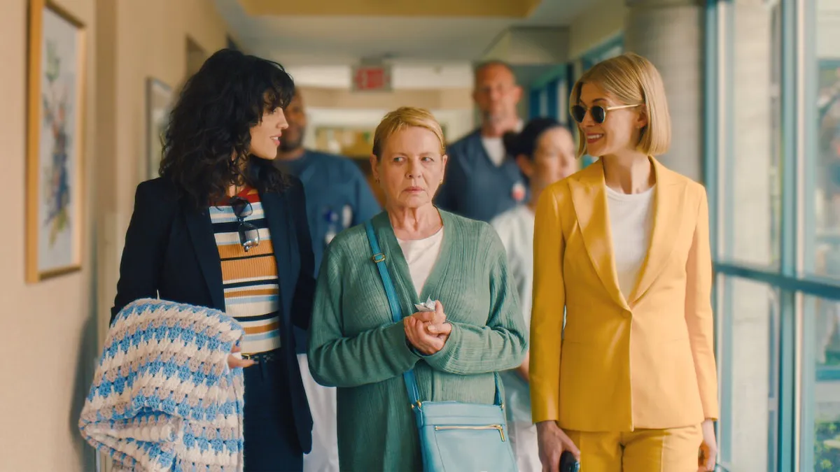Three women walk down a hallway and talk in "I Care A Lot" 
