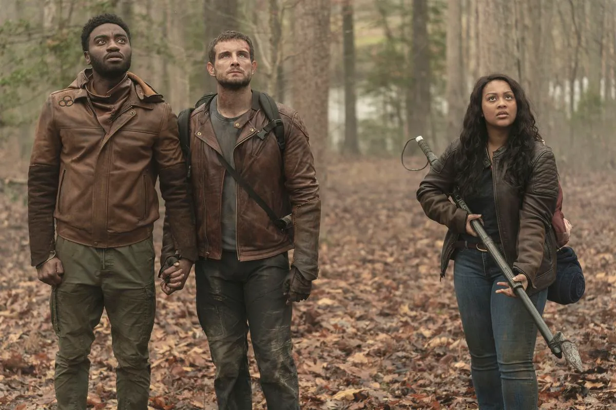 Jelani Alladin as Will Campbell holding hands with Nico Tortorella as Felix Carlucci, and Aliyah Royale as Iris Bennett in The Walking Dead: World Beyond season 2