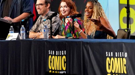 Jonah Ray Rodrigues (white man, glasses, dark hair), Felicia Day (white woman, red hair), and London Hughes (Black woman, long, curly blonde hair) speak onstage during The 
