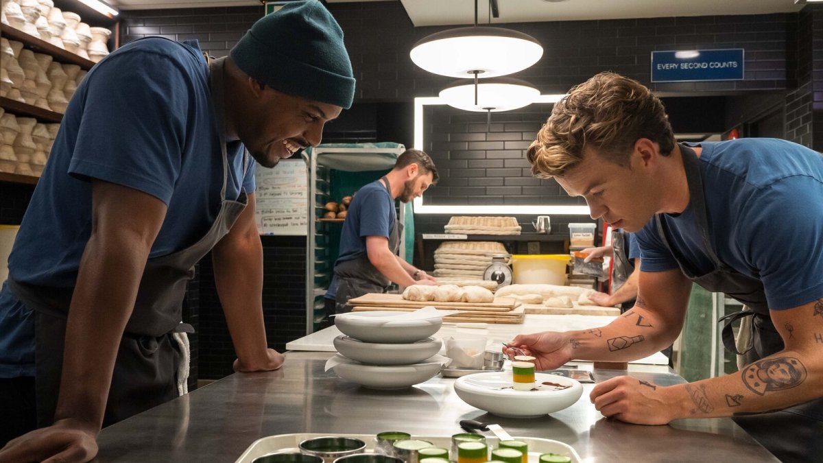 Two men in a restaurant kitchen perfecting a dessert.