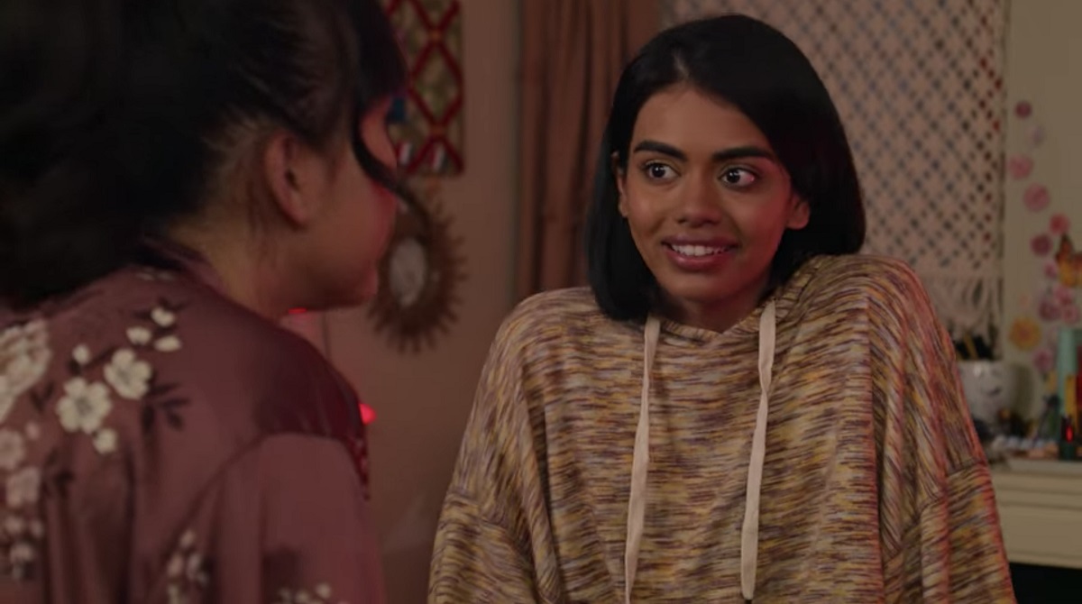 Megan Suri as Aneesa in a scene from Netflix's 'Never Have I Ever.'  Samidha is an Indian-American teenage girl with chin-length dark hair. We see her smiling in medium close-up wearing a multicolored pullover hoodie as she talks to a friend. 