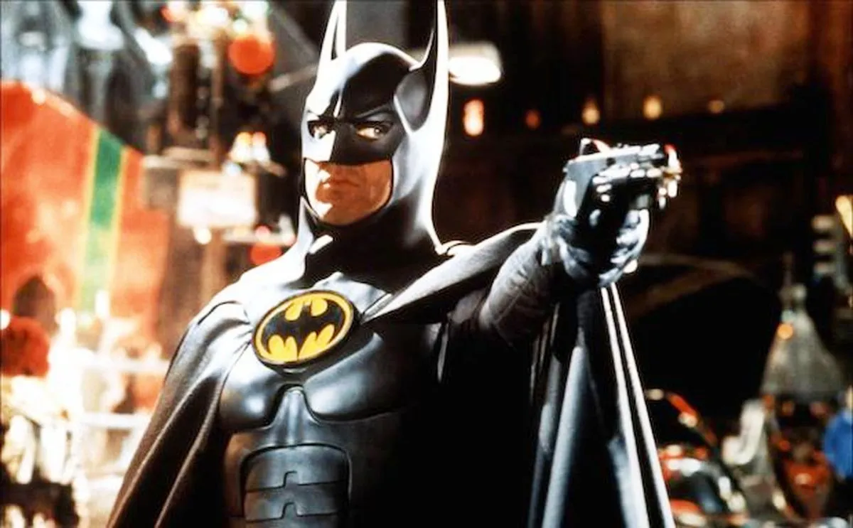 Michael Keaton as Bruce Wayne posing with a gun aimed at someone in "Batman Returns"