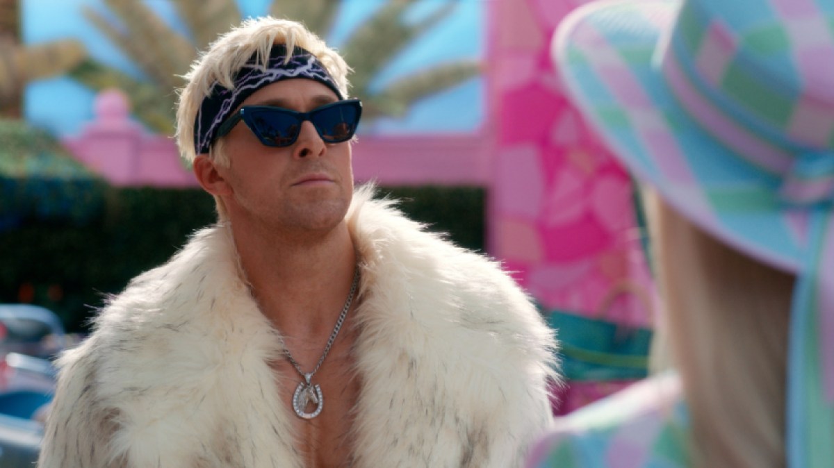 Ryan Gosling as Ken in "Barbie" wearing a fur jacket and sunglasses posing smoothly.