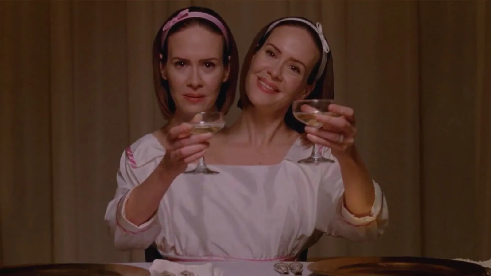 Sarah Paulson as Bette and Dot raising their glasses in American Horror Story: Freak Show