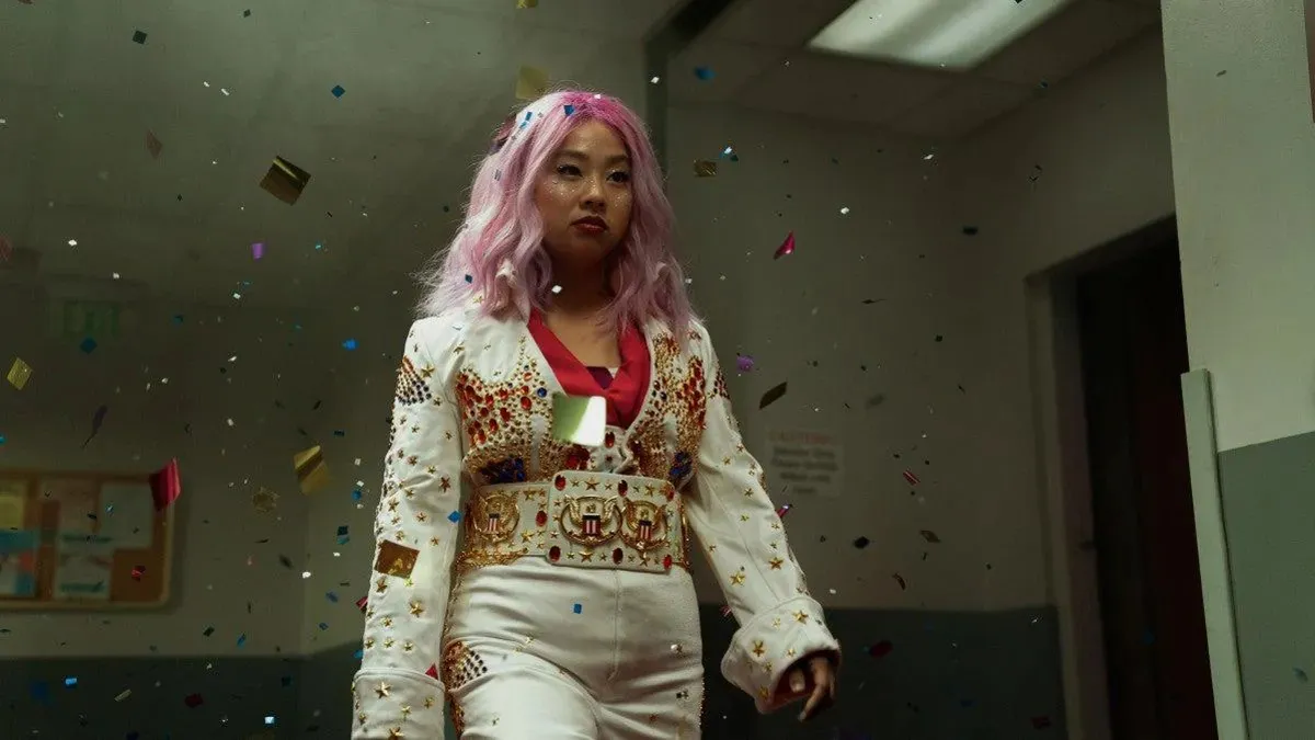 Stephanie Hsu in "Everything Everywhere All At Once" wearing a costume reminiscent of 1970s Elvis Presley, surrounded by metallic confetti.