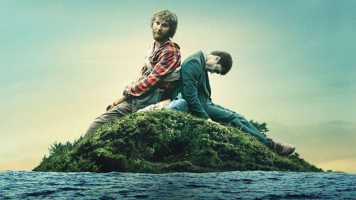Paul Dano leaning back-to-back with a corpse-like Daniel Radcliffe on a tiny island in the middle of the ocean, from the film "Swiss Army Man"