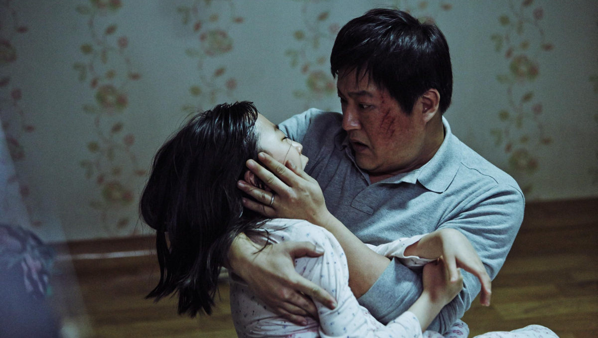 A man cradles his ill daughter in 'The Wailing'