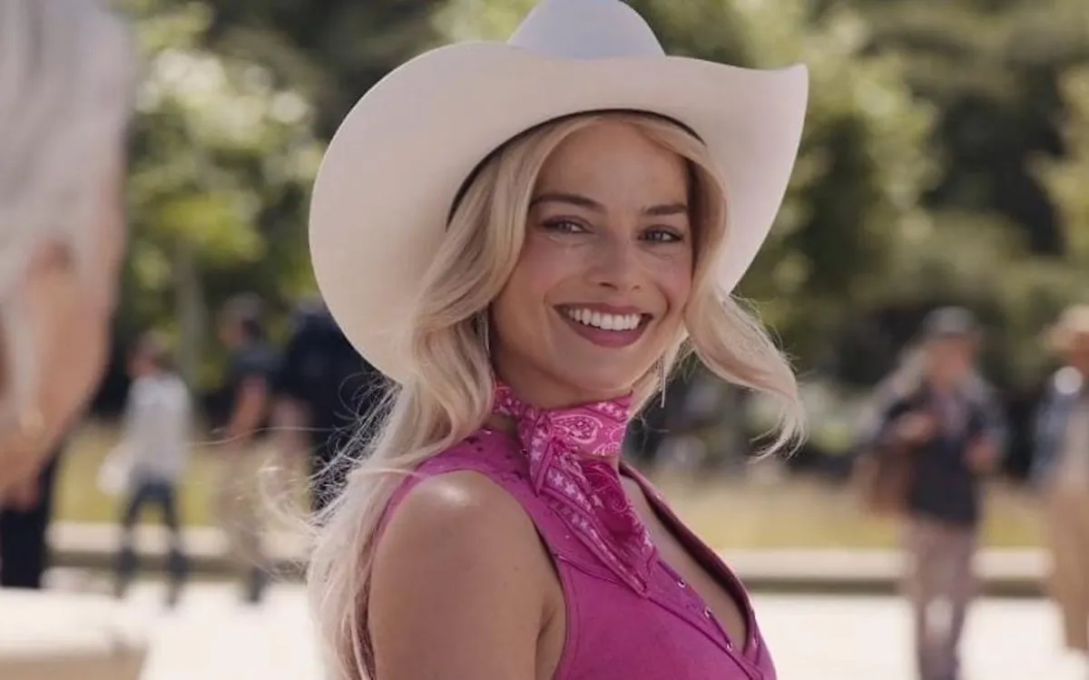 Margot Robbie smiles, dressed as Cowgirl Barbie.