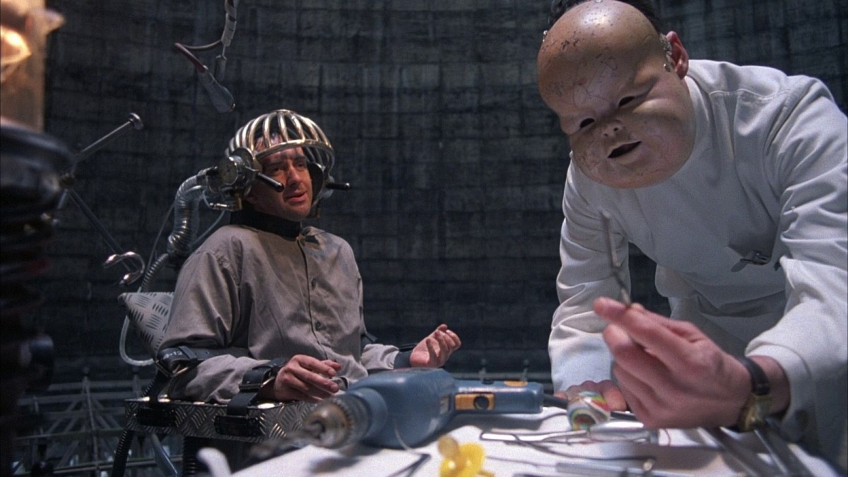 A white man is trapped in a chair while a doctor with a baby's head gets ready to work on him in "Brazil"