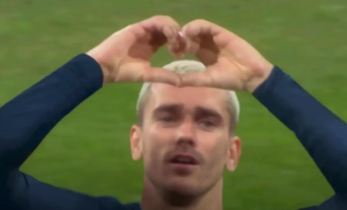 A male soccer player making a heart gesture with his hands.