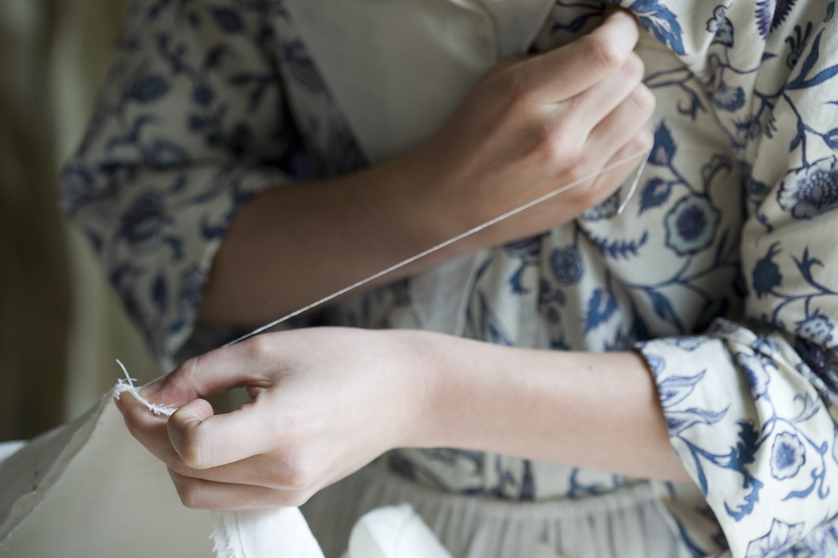 A colonial actor in Williamsburg Virginia shows her sewing technique