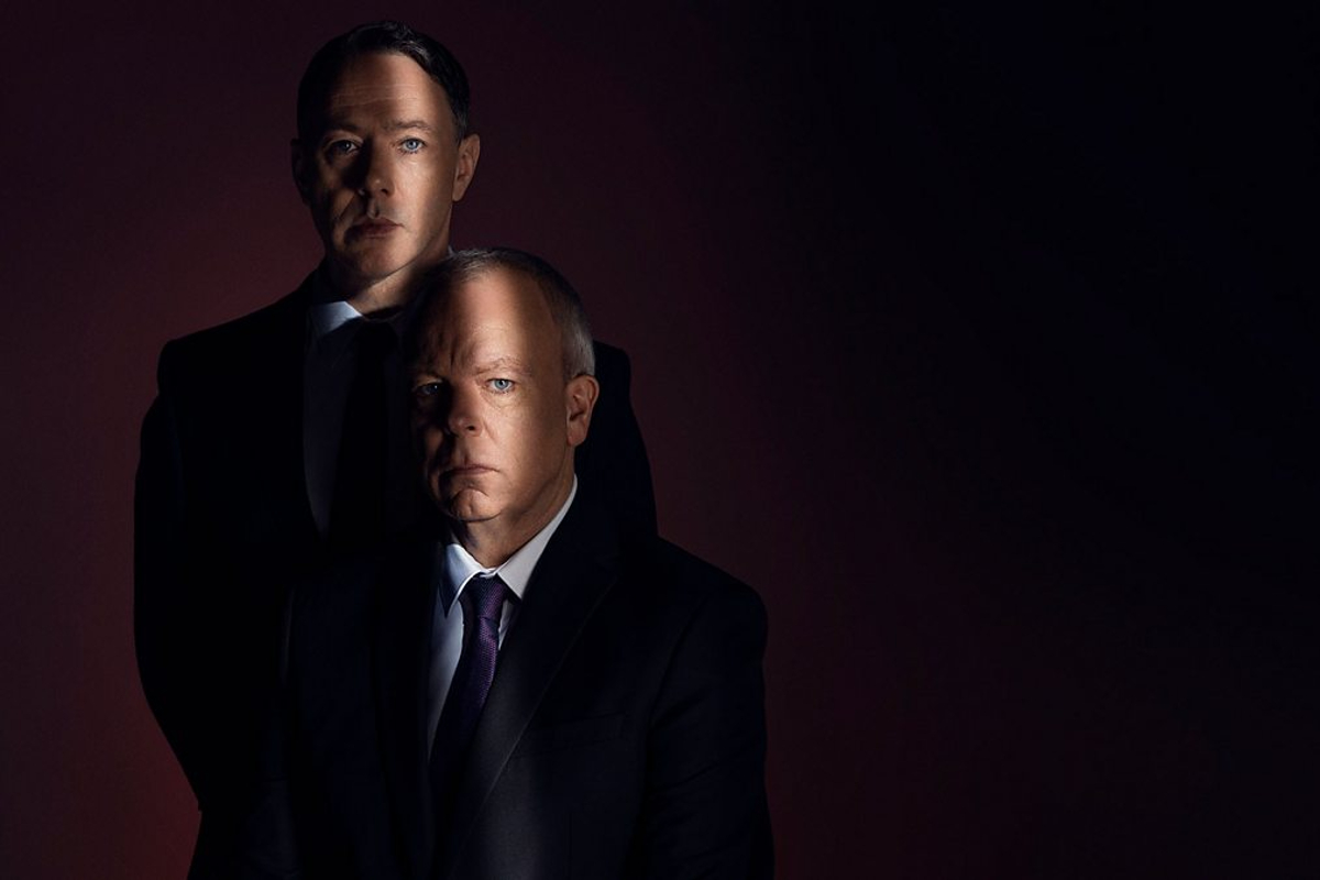Inside no. 9 promotional image. Two white men in suits (Reece Shearsmith and Steve Pemberton) sit in a darkened room looking ominous