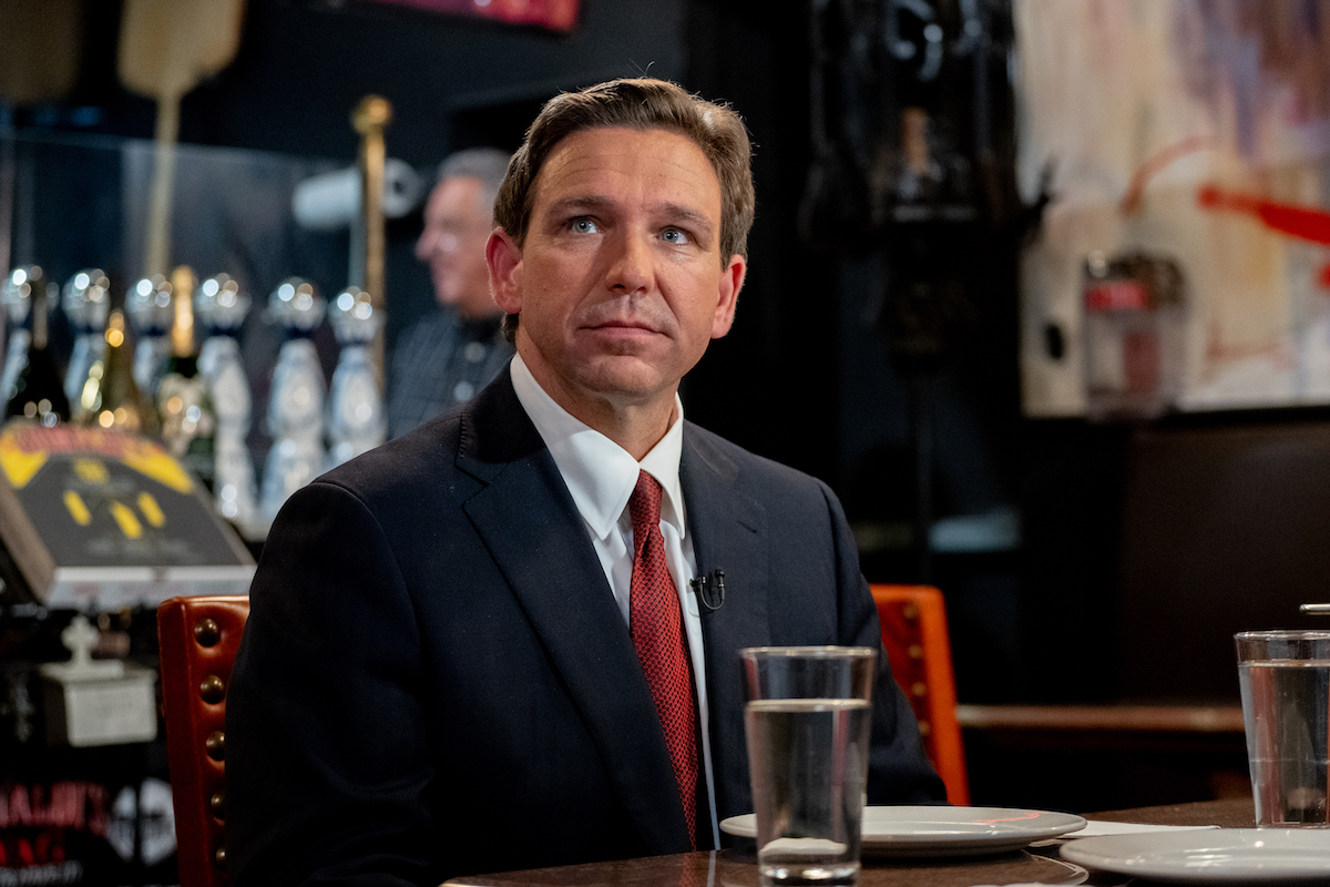Ron DeSantis sits in a restaurant, staring off wistfully.