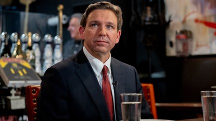 Ron DeSantis sits in a restaurant, staring off wistfully.