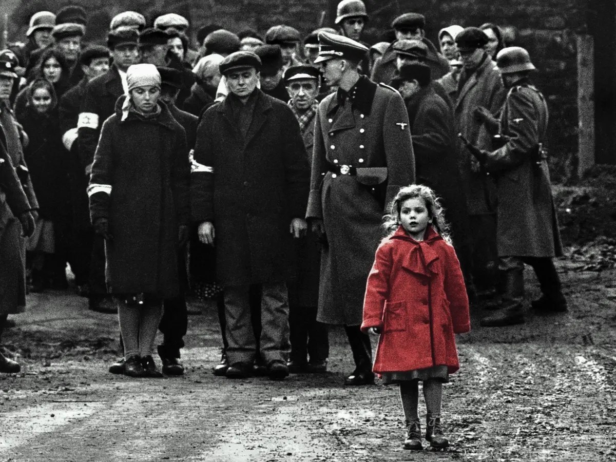 The girl in the red coat stands in front of a crowd in Schindler's List 