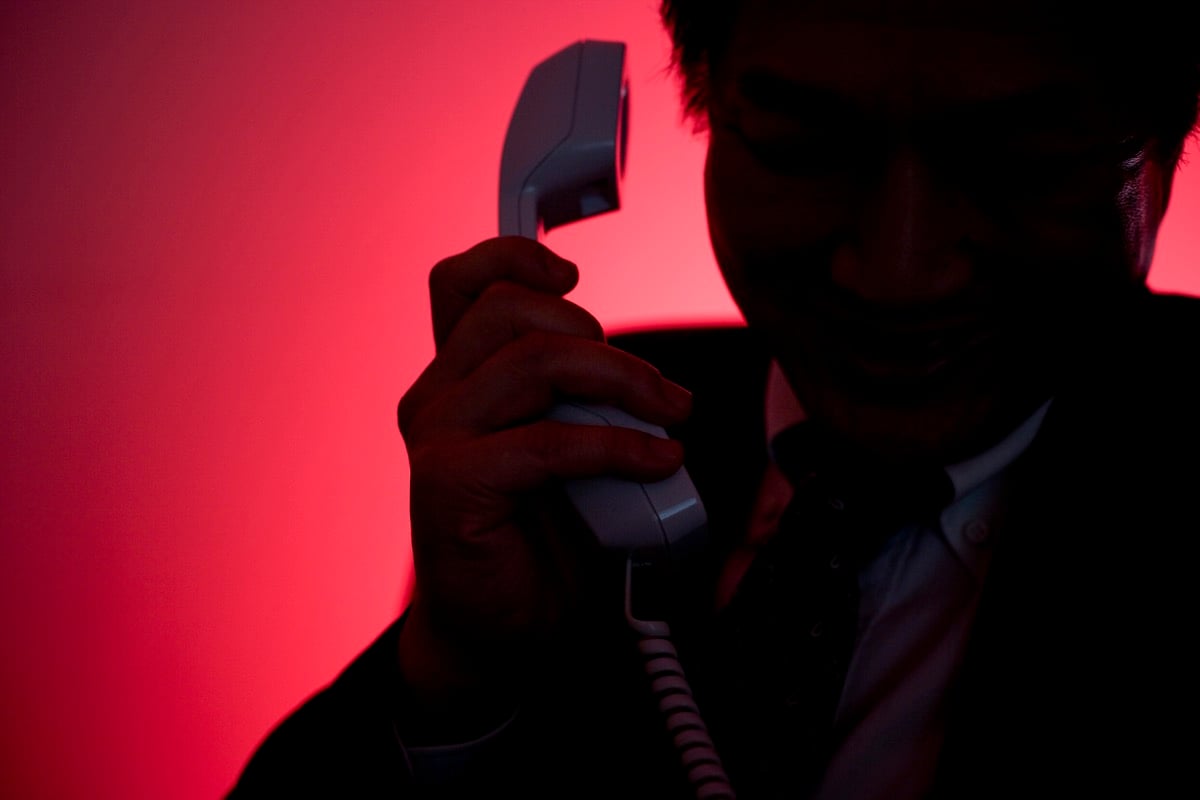 Silhouette of man making a phone call against a dramatic red background.