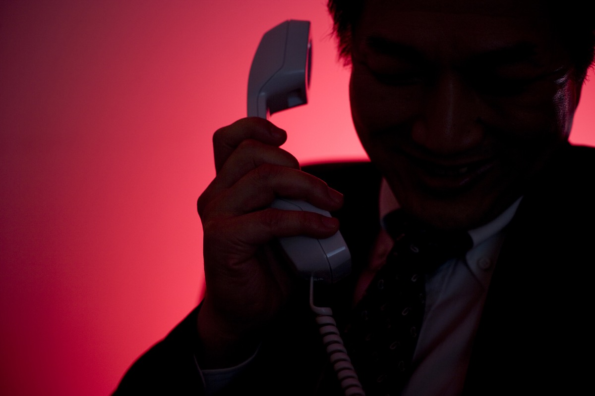 Silhouette of man making a phone call against a dramatic red background.
