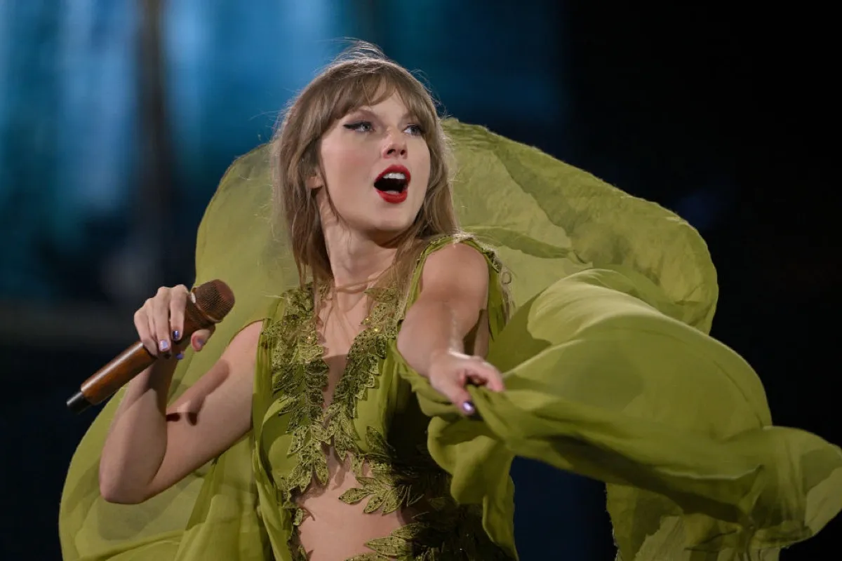 Taylor Swift performing on stage in a flowy green dress during The Eras Tour.