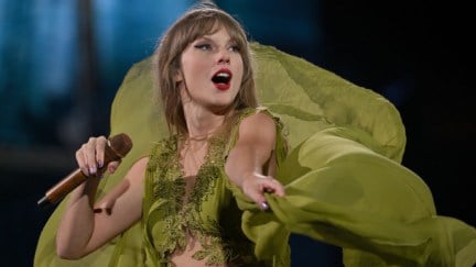 Taylor Swift performing on stage in a flowy green dress during The Eras Tour.